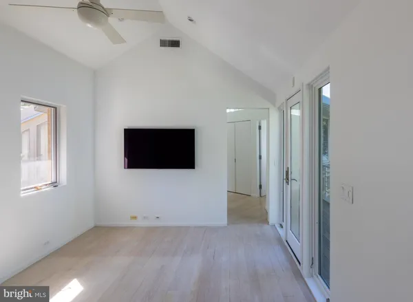 a view of an empty room with wooden floor and floor to ceiling window