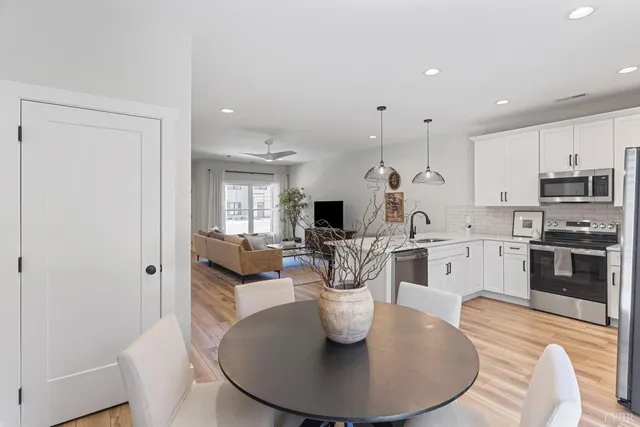 a kitchen with stainless steel appliances kitchen island granite countertop a stove a sink a dining table and chairs