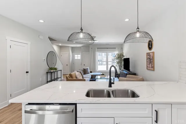 a kitchen with a sink a chandelier and living room view