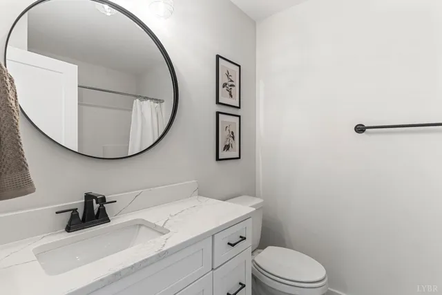 a bathroom with a granite countertop toilet sink mirror and vanity