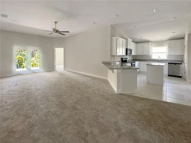 a kitchen with stainless steel appliances a large counter top a sink a stove a refrigerator cabinets and a window