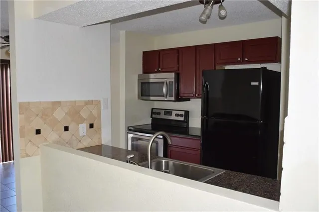 a kitchen with stainless steel appliances kitchen island granite countertop a refrigerator and a stove top oven