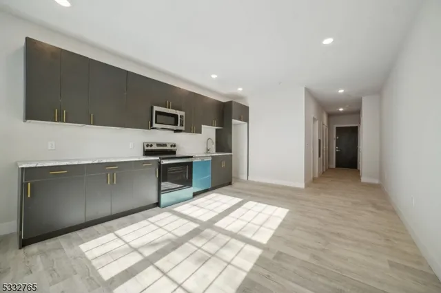 a kitchen with stainless steel appliances kitchen island granite countertop a refrigerator and a sink