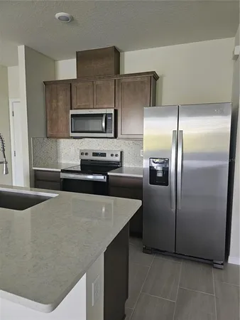 a kitchen with stainless steel appliances granite countertop a sink and a refrigerator