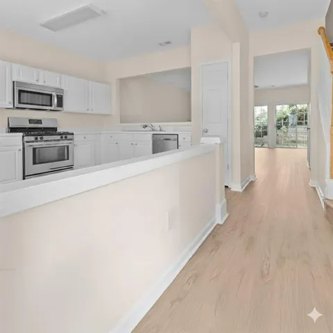 a kitchen with stainless steel appliances a microwave a sink a stove and white cabinets