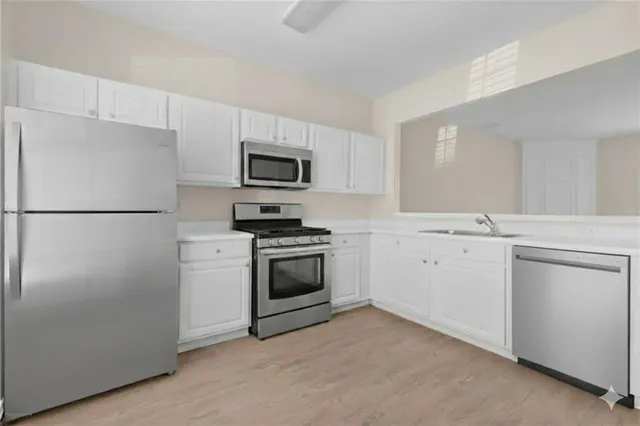 a kitchen with cabinets stainless steel appliances and sink