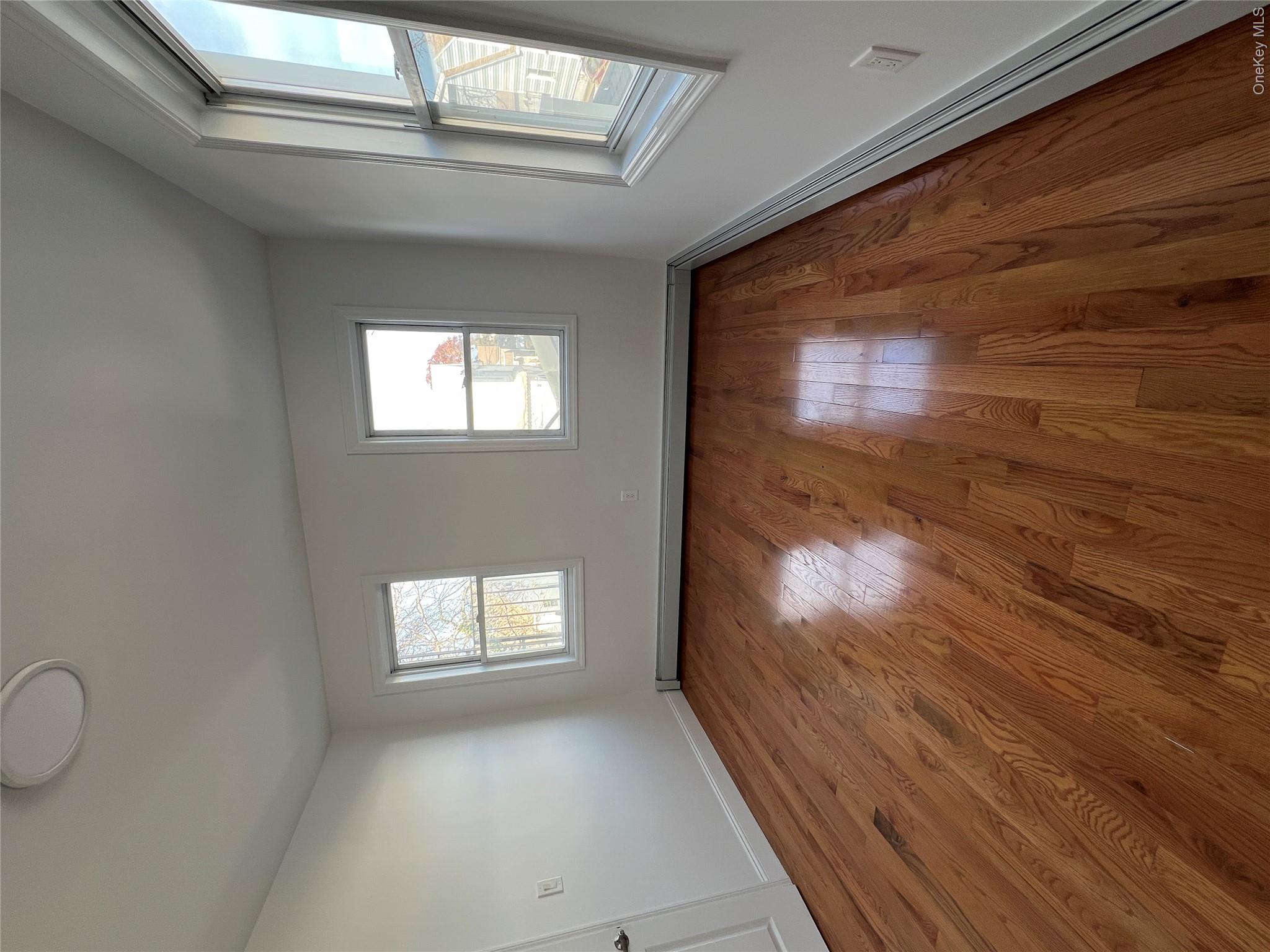 216-25 136th Road, Unit 1 2 AND 3 Queens, NY 11413 - Photo 18 of 43 an empty room with wooden floor and windows