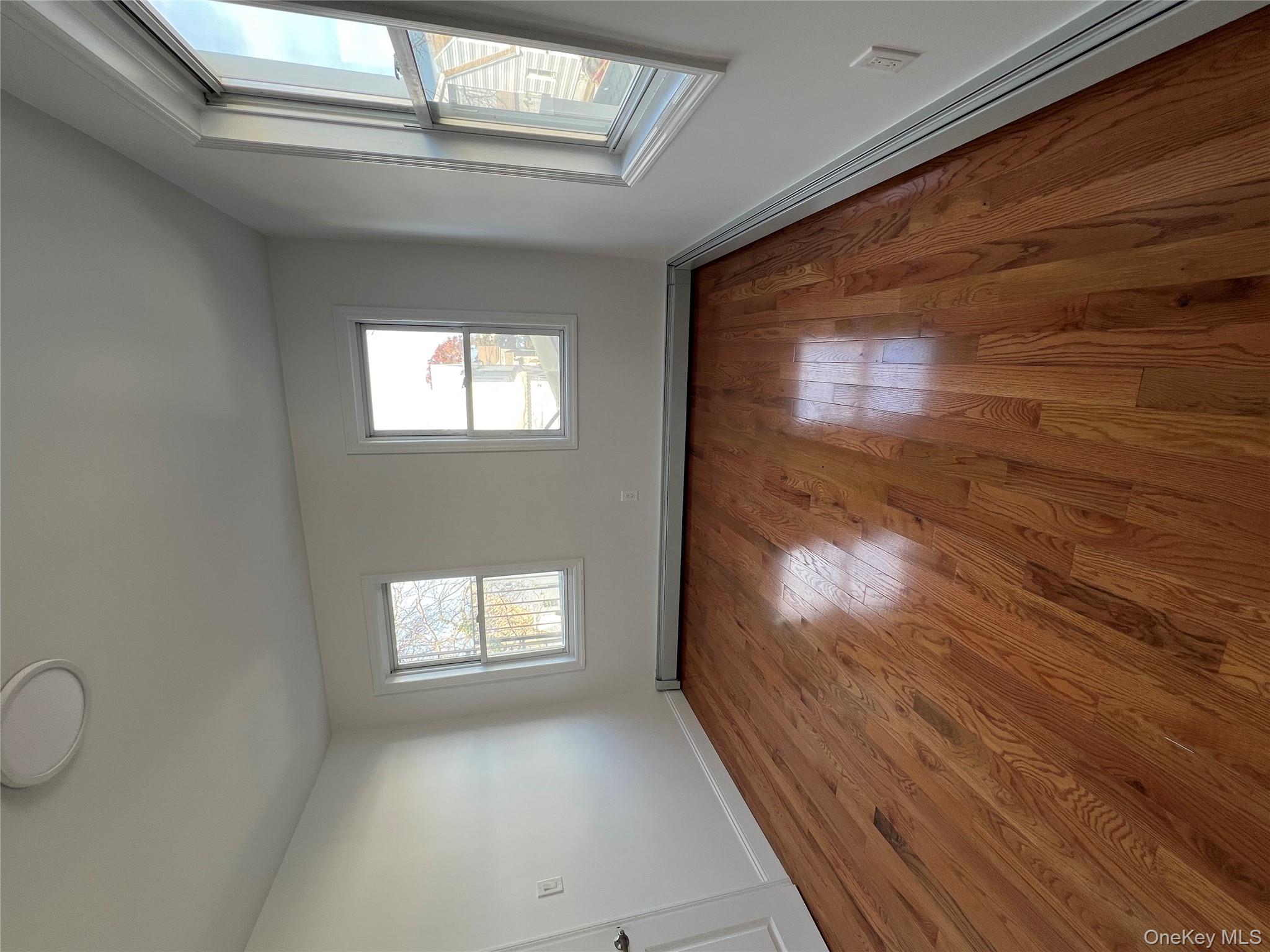 216-25 136th Road, Unit 1 2 AND 3 Queens, NY 11413 - Photo 18 of 43 an empty room with wooden floor and windows