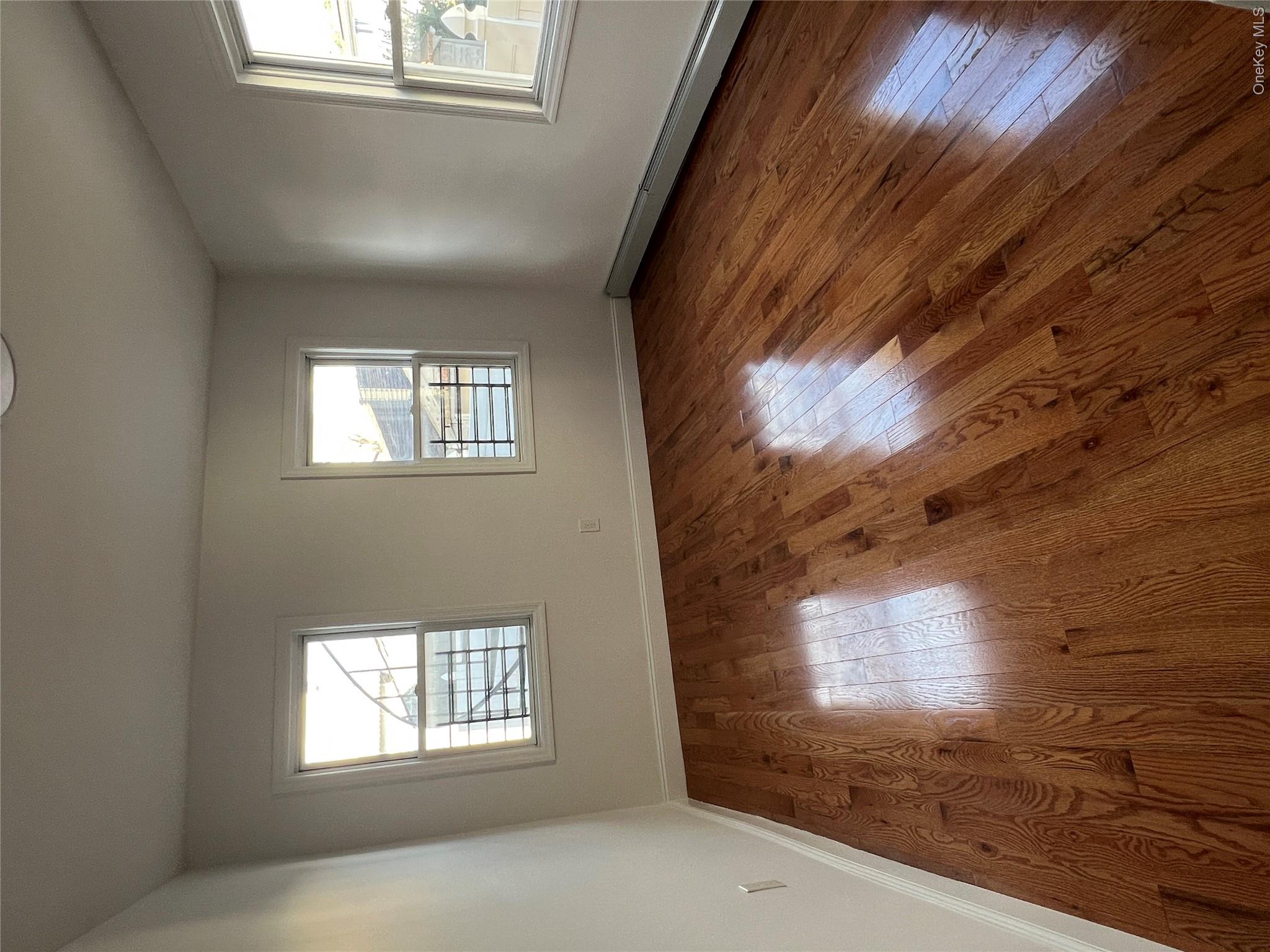 216-25 136th Road, Unit 1 2 AND 3 Queens, NY 11413 - Photo 7 of 43 an empty room with wooden floor and windows