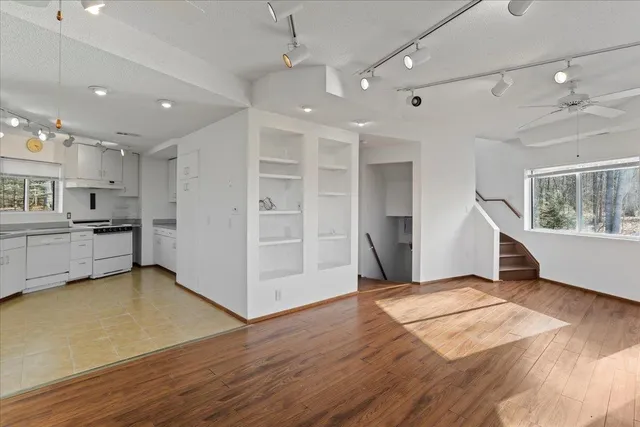 a view of an empty room with wooden floor and a window