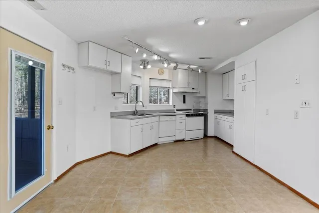 a kitchen that has a lot of white cabinets and stainless steel appliances