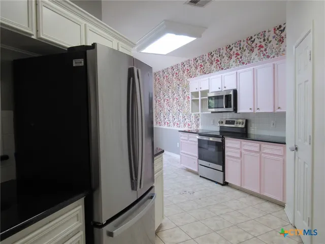a kitchen with stainless steel appliances granite countertop a refrigerator and a stove top oven