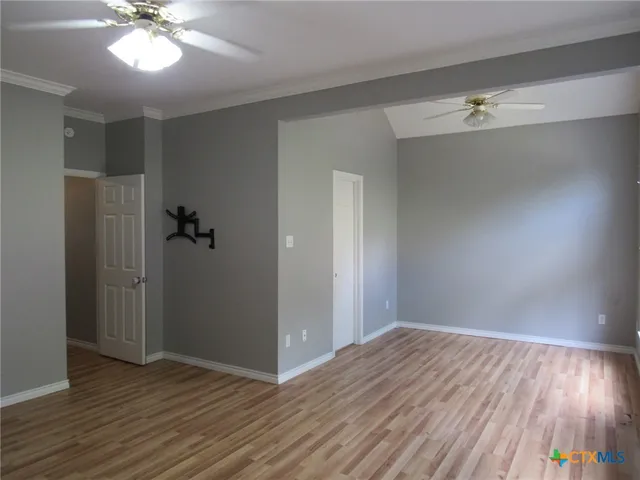 a view of empty room with wooden floor and fan