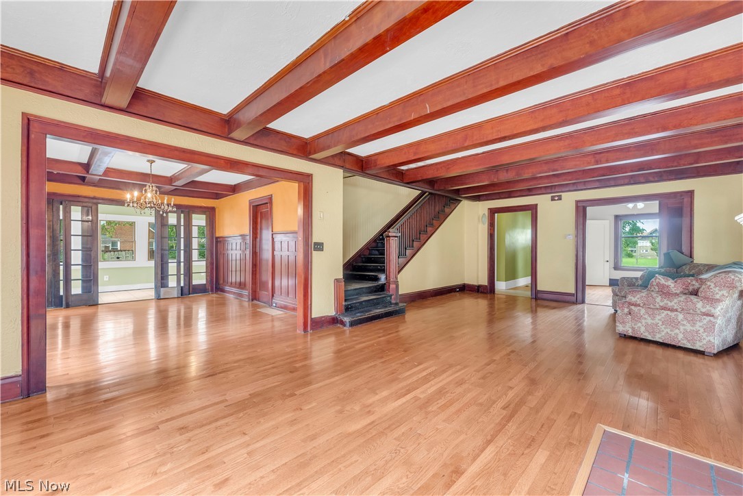 17406 Nottingham Road Cleveland, OH 44119 - Photo 4 of 45 Hardwood flooring throughout, exposed wood ceiling beams, wood trim details, wood staircase, and French doors with transom windows