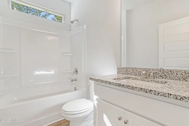 a bathroom with a granite countertop sink a toilet and shower