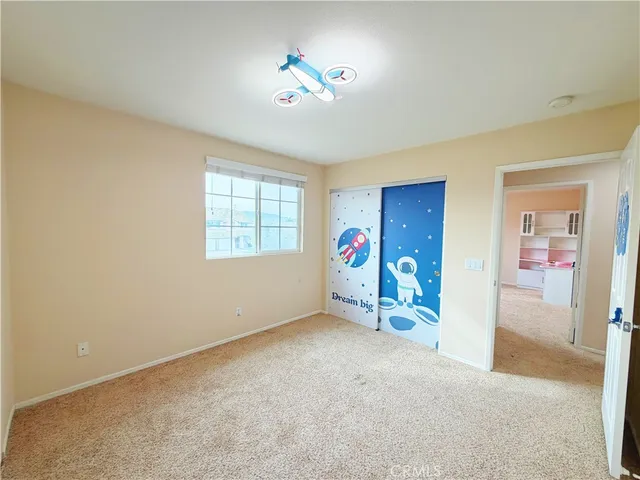 an empty room with closet and a chandelier fan