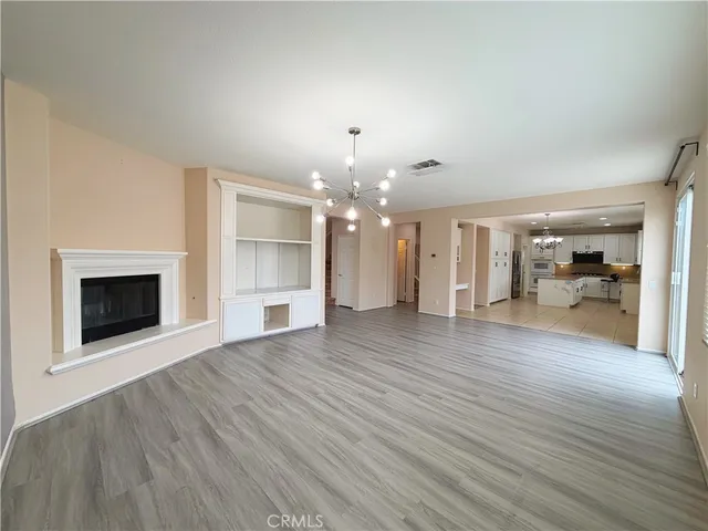 a view of a livingroom with wooden floor and a kitchen