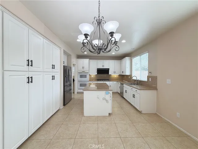 a kitchen with a chandelier stainless steel appliances cabinets and a counter top space