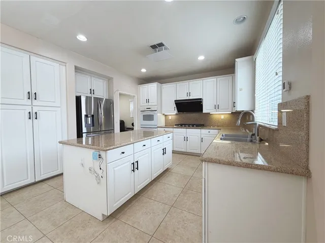 a kitchen with granite countertop white cabinets and stainless steel appliances