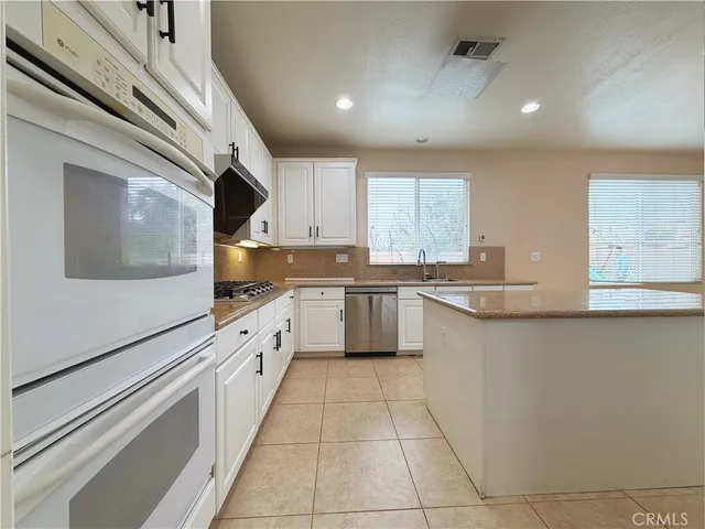 a large kitchen with stainless steel appliances lots of counter top space cabinets and a sink