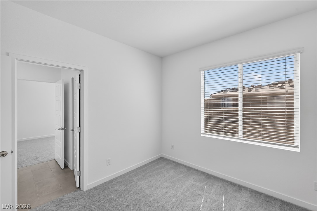 347 Sam Way Mesquite, NV 89027 - Photo 16 of 32 A well-lit bedroom features plush gray carpet and a large window with privacy blinds.