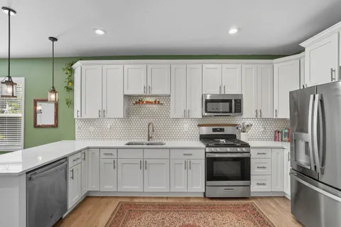 a kitchen with kitchen island white cabinets stainless steel appliances and sink