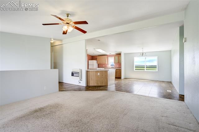 1435 Equestrian Point Yoder, CO 80864 - Photo 12 of 49 Unfurnished living room with heating unit, carpet floors, ceiling fan, and tile patterned floors