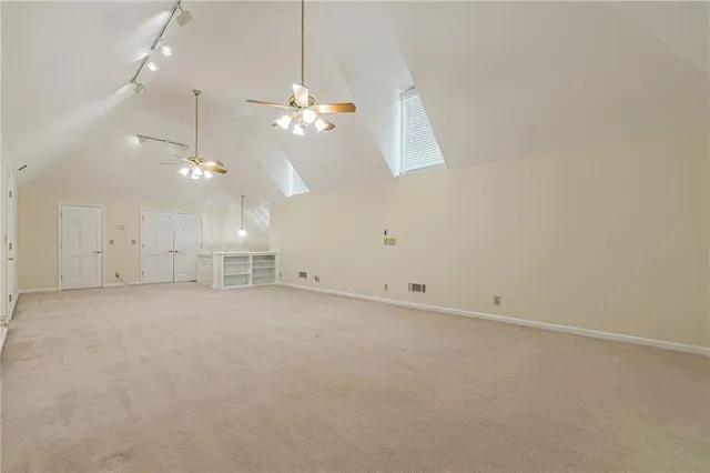 an empty room with chandelier fan and windows