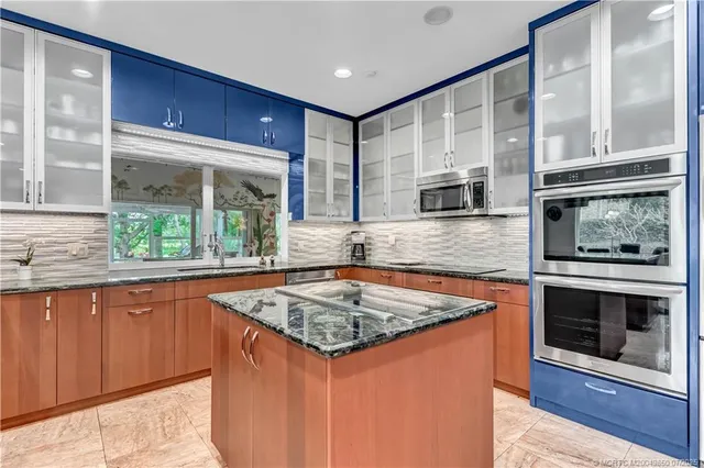 a kitchen with stainless steel appliances granite countertop sink stove and large window