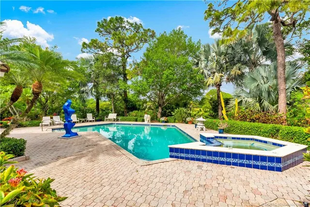 a view of swimming pool with lawn chairs and plants