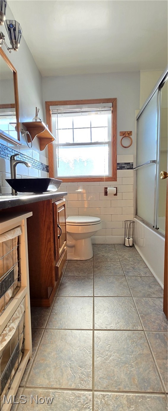 5217 McCartney Road Sandusky, OH 44870 - Photo 13 of 17 Full bathroom with combined bath / shower with glass door, toilet, tile walls, and vanity