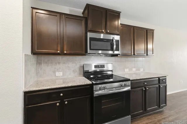 a kitchen with granite countertop wooden cabinets and a stove top oven