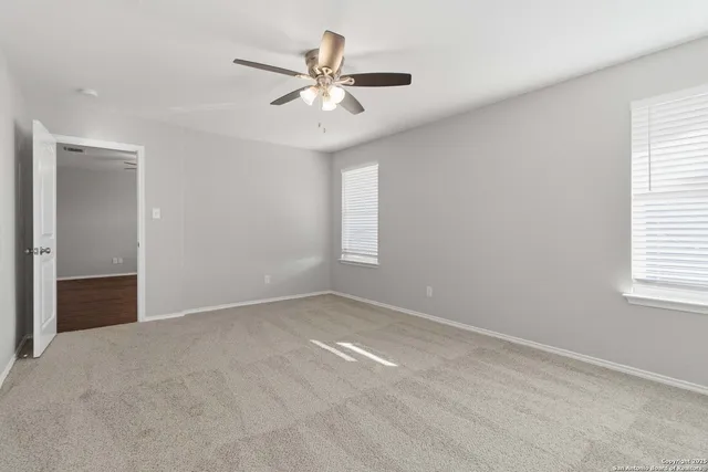 an empty room with windows and fan