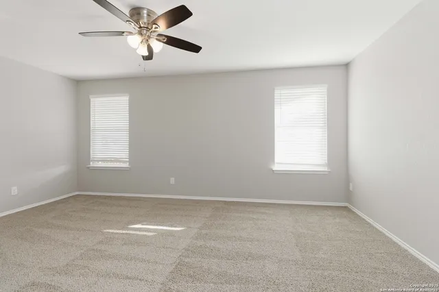 an empty room with a window and a fan