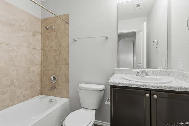 a bathroom with a granite countertop toilet a sink and a bathtub