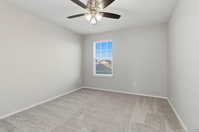 an empty room with a chandelier fan and windows