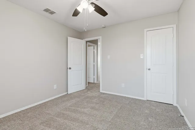 an empty room with a ceiling fan and a window