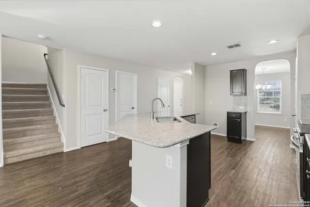 a open kitchen with white cabinets appliances and wooden floor