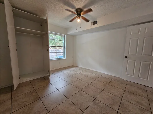 an empty room with windows and fan