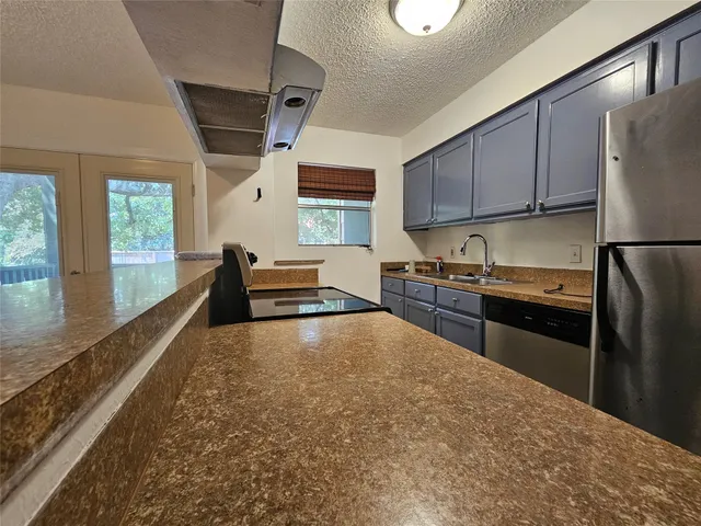 a kitchen with stainless steel appliances granite countertop a refrigerator sink and stove