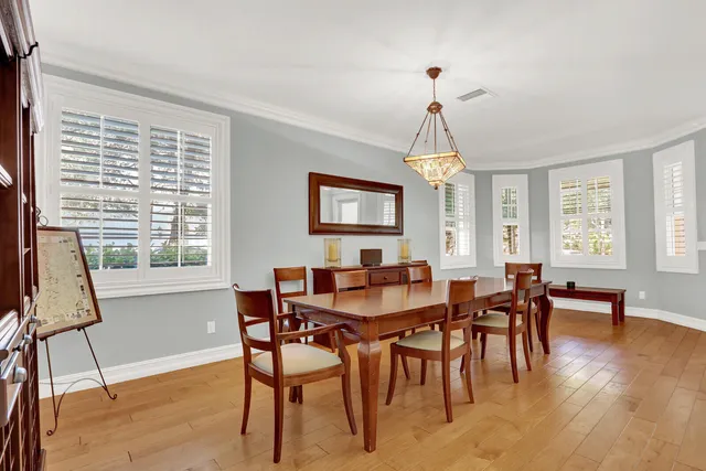a dining room with wooden floor a chandelier a wooden table and chairs