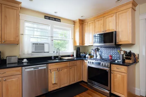 a kitchen with stainless steel appliances granite countertop a stove a sink dishwasher and cabinets with wooden floor