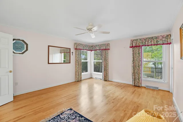 a view of an empty room with a window and wooden floor