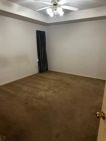 an empty room with a ceiling fan and a window