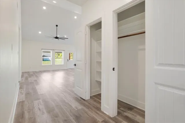 a view of an empty room with wooden floor and windows