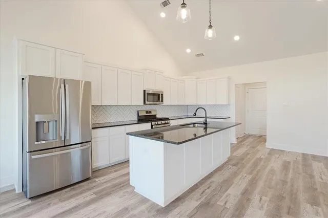 a kitchen with stainless steel appliances a sink a stove a refrigerator and cabinets