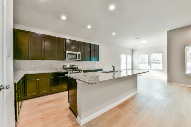 a kitchen with stainless steel appliances granite countertop a stove a sink and a microwave