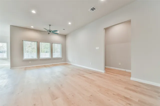 an empty room with wooden floor and windows