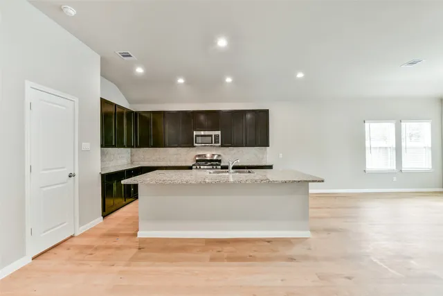 a view of kitchen with stainless steel appliances granite countertop a sink a stove and a refrigerator