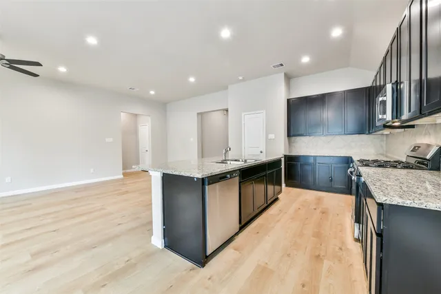 a kitchen with stainless steel appliances granite countertop a stove a sink and a refrigerator